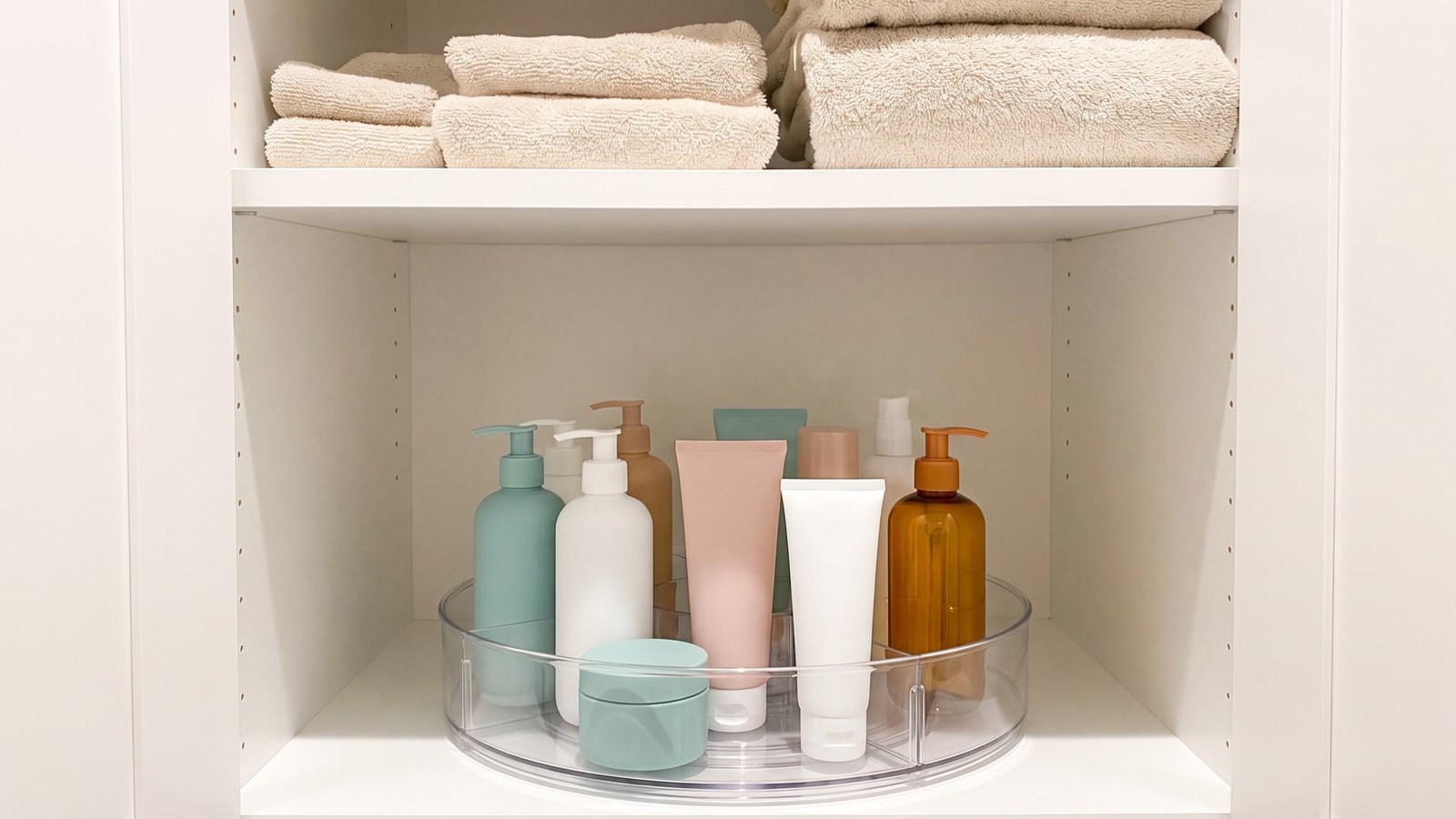 Clear lazy Susan turntable organizing toiletries in a bathroom cabinet